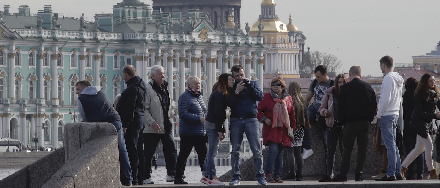 Foto: Menschen gehen an der Promenade des Flusses Newa vor dem Winterpalast in St. Petersburg entlang.